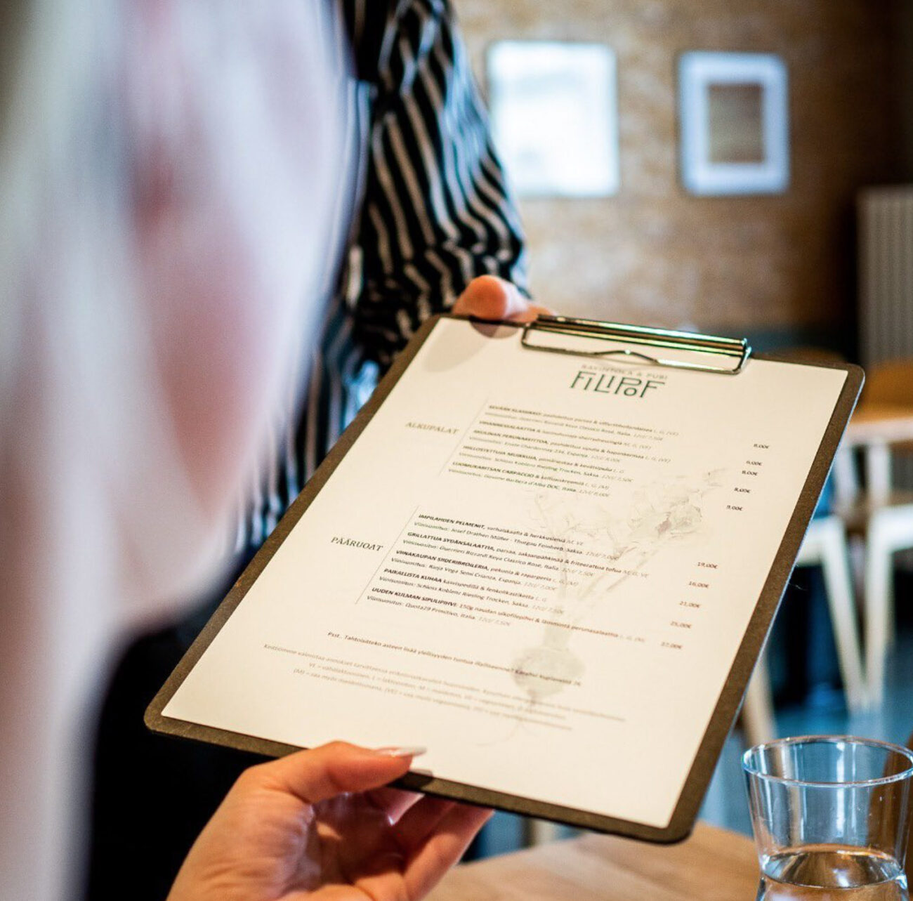 Lähikuva Ravintola Filipofin menusta jota ojennetaan asiakkaalle.